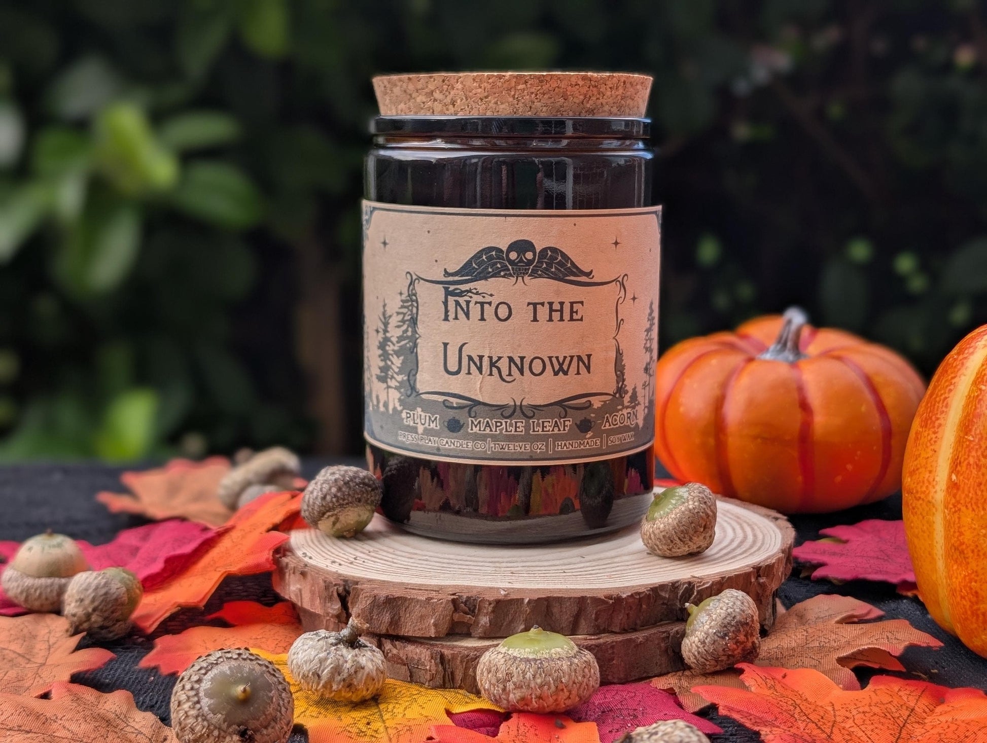 Into the Unknown candle inspired by Over the Garden Wall, plum, maple leaf, and acorn fragrance in amber glass jar.